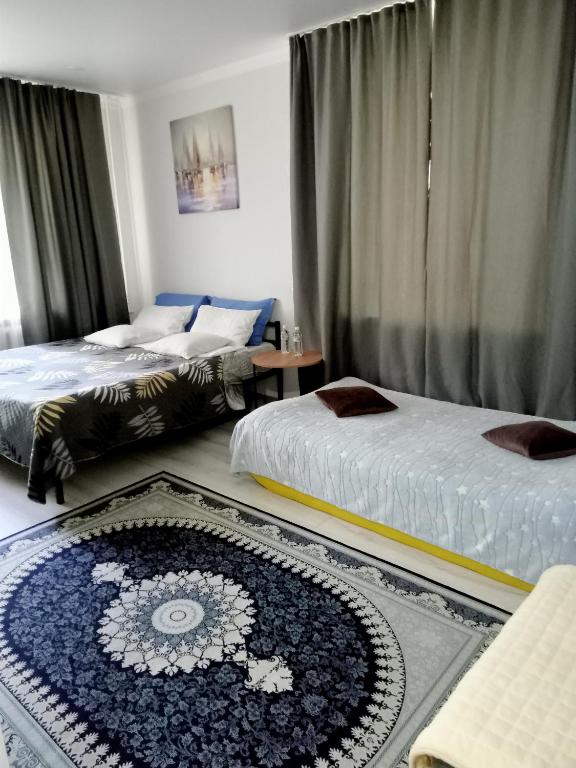 a bedroom with two beds and a rug on the floor at Family Home in Petropavlovsk