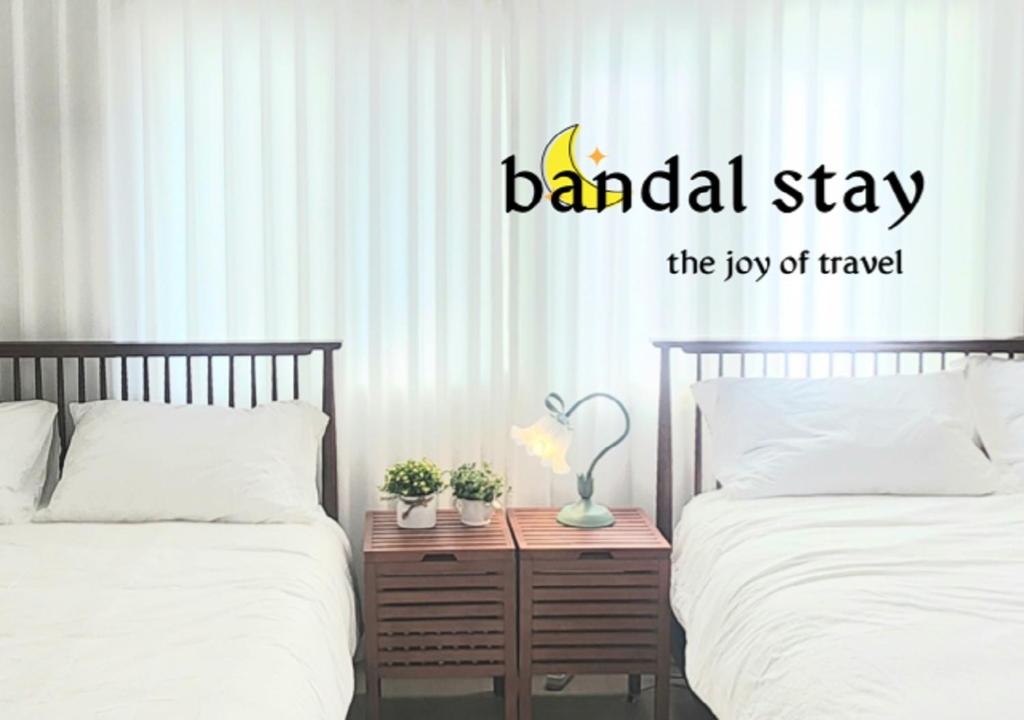 een slaapkamer met twee bedden en een bordje met de tekst bandled stay the joy bij Bandal Stay in Daegu in Daegu