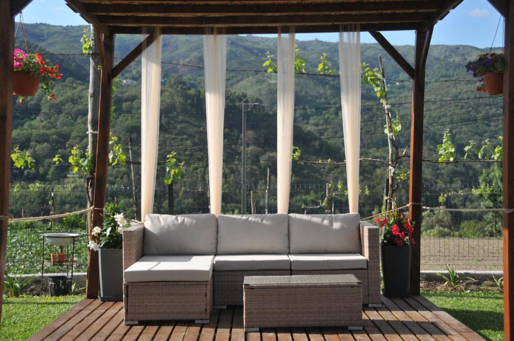 Un sofá sentado en una terraza con un cenador. en Quinta da Lagoa - Gerês, en Terras de Bouro