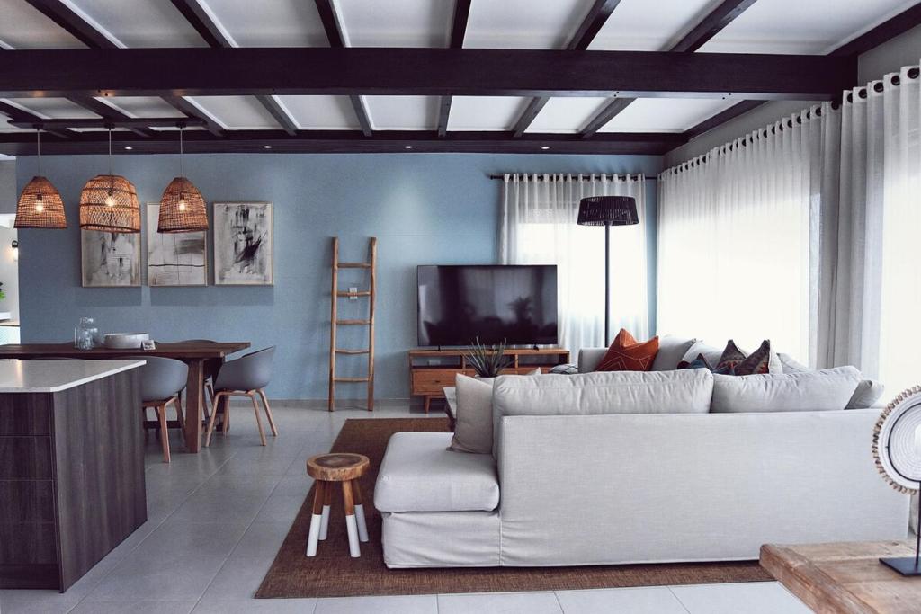 a living room with a white couch and a kitchen at Palm Villa Beachfront Accomodation in Hentiesbaai