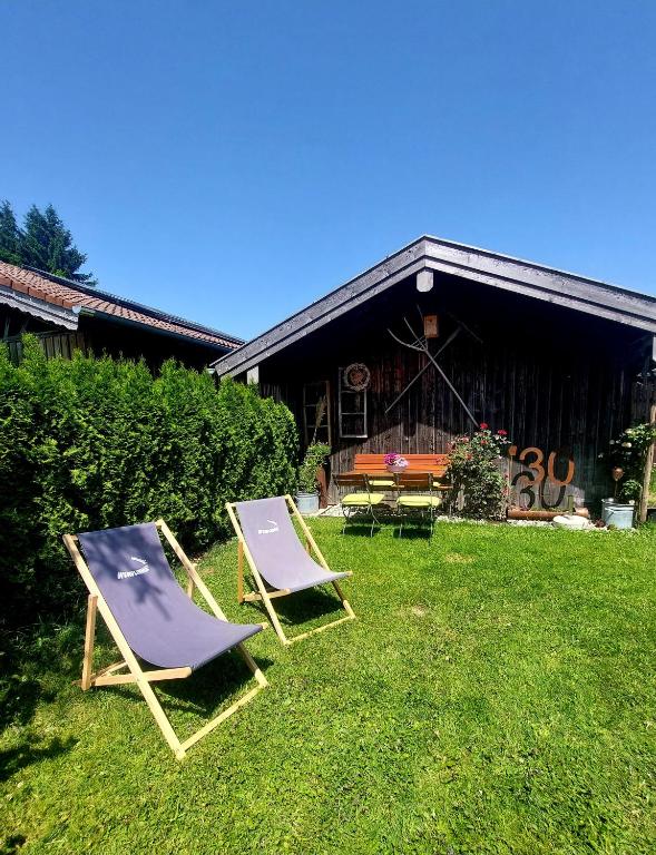 two lawn chairs sitting in the grass in front of a building at Ferienwohnung Schneckenpointner in Waging am See
