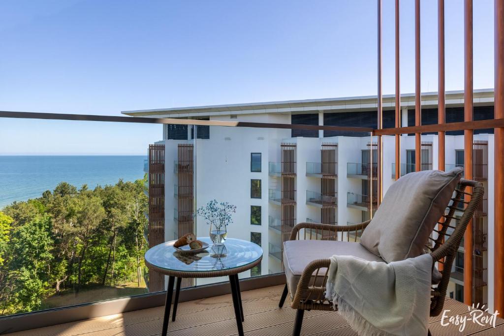 a balcony with a chair and a table and the ocean at Prestige Pinea 713 - Easy - Rent Apartments in Pobierowo
