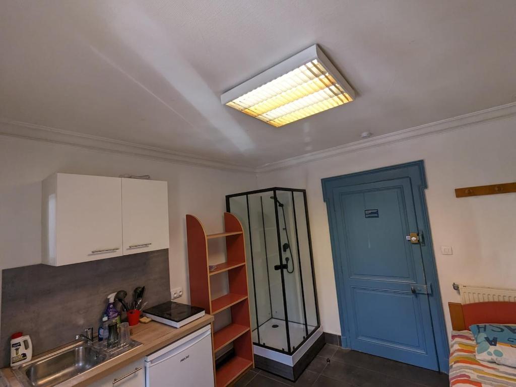 - une cuisine avec un évier et une porte bleue dans l'établissement Studio Centre-Ville with shared toilets, à Chambéry