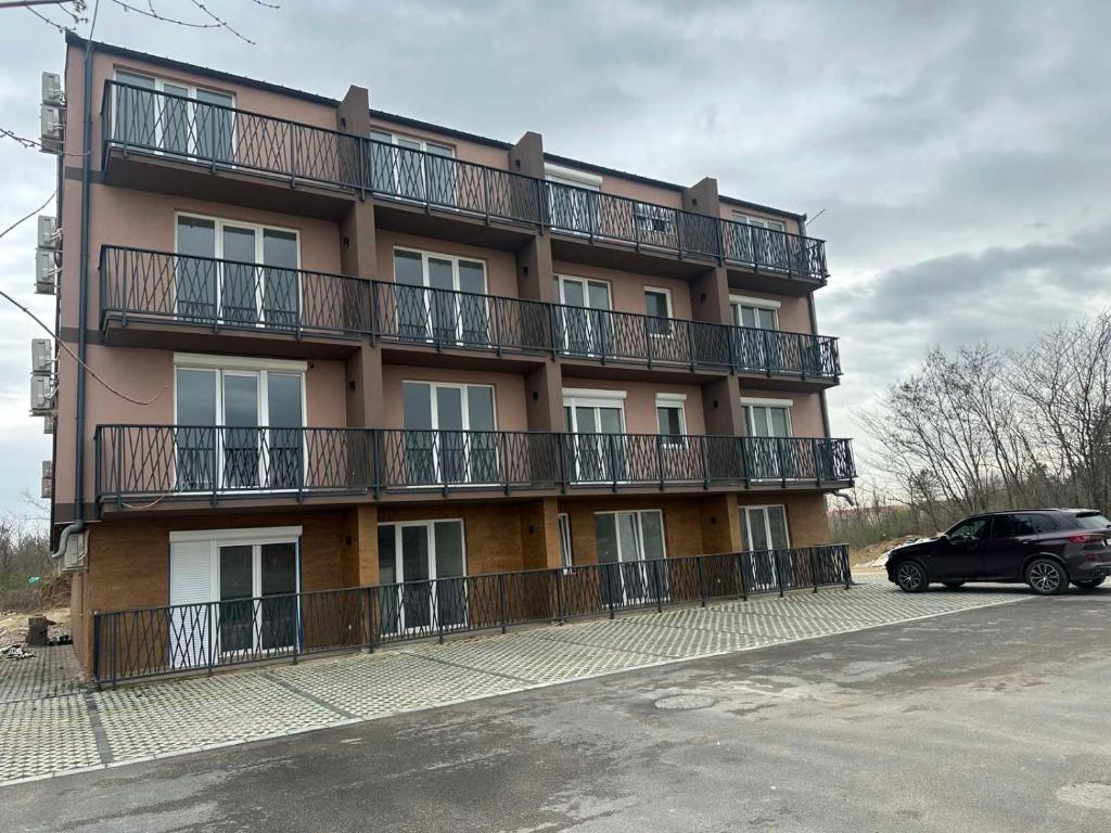 a building with balconies and a car parked in front of it at Nobus Jezerska zvezda A7 in Veliko Gradište