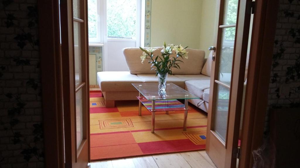 una sala de estar con sofá y un jarrón de flores sobre una mesa en Harmony Life Two-room apartment in Riga en Riga