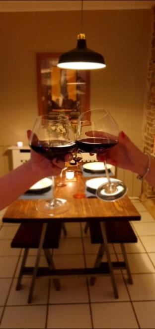 une personne tenant deux verres de vin sur une table dans l'établissement La petite Maison, à Argenton-Château