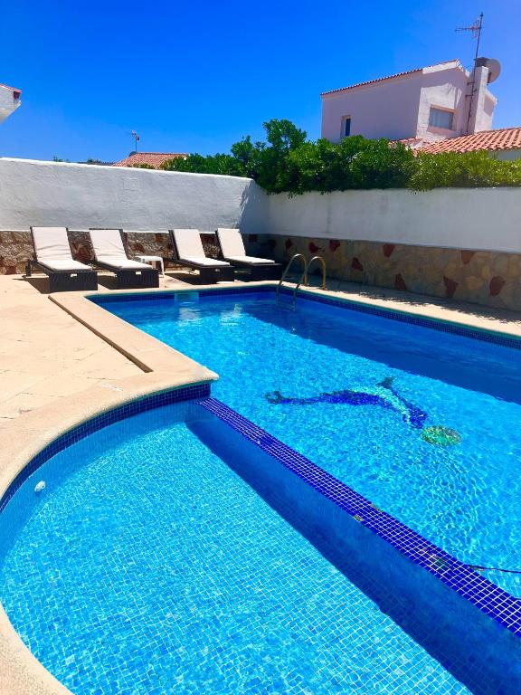 a swimming pool with chairs next to a building at Chalets con piscinas privadas junto al mar in Cala en Bosc