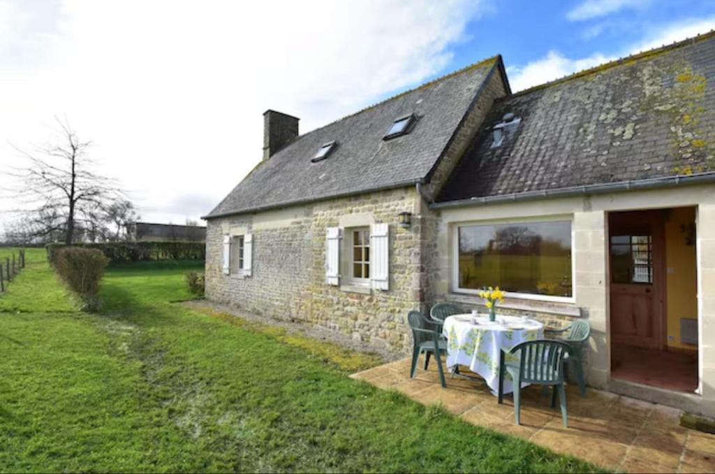une maison en pierre avec une table et des chaises dans une cour dans l'établissement Gîte du Netz, à Appeville