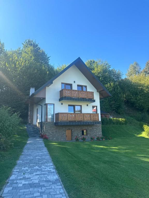 a large white house with a balcony and a lawn at Pod Dębem in Zabrzeź