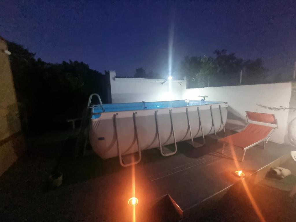 Una piscina de noche con dos sillas y luces. en OpenSpace in Villa Serroni Mazara, en Mazara del Vallo