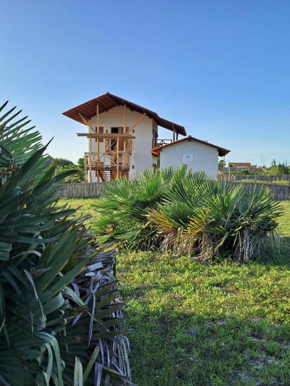a house in a field with palm trees at Casa Vento - 2 Andares e Cozinha in Luis Correia