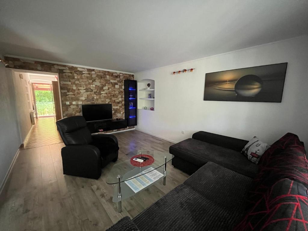 a living room with a black couch and chairs at Âme de la nature in Nedeščina