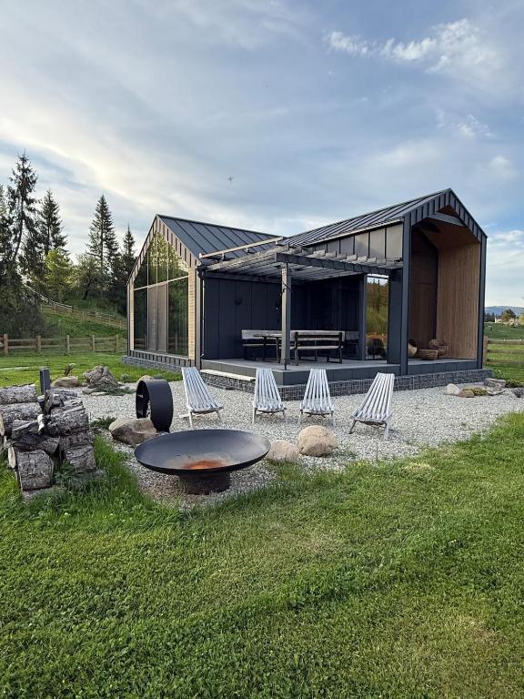a building with chairs and a table in the grass at The Prut Lodge in Vorokhta