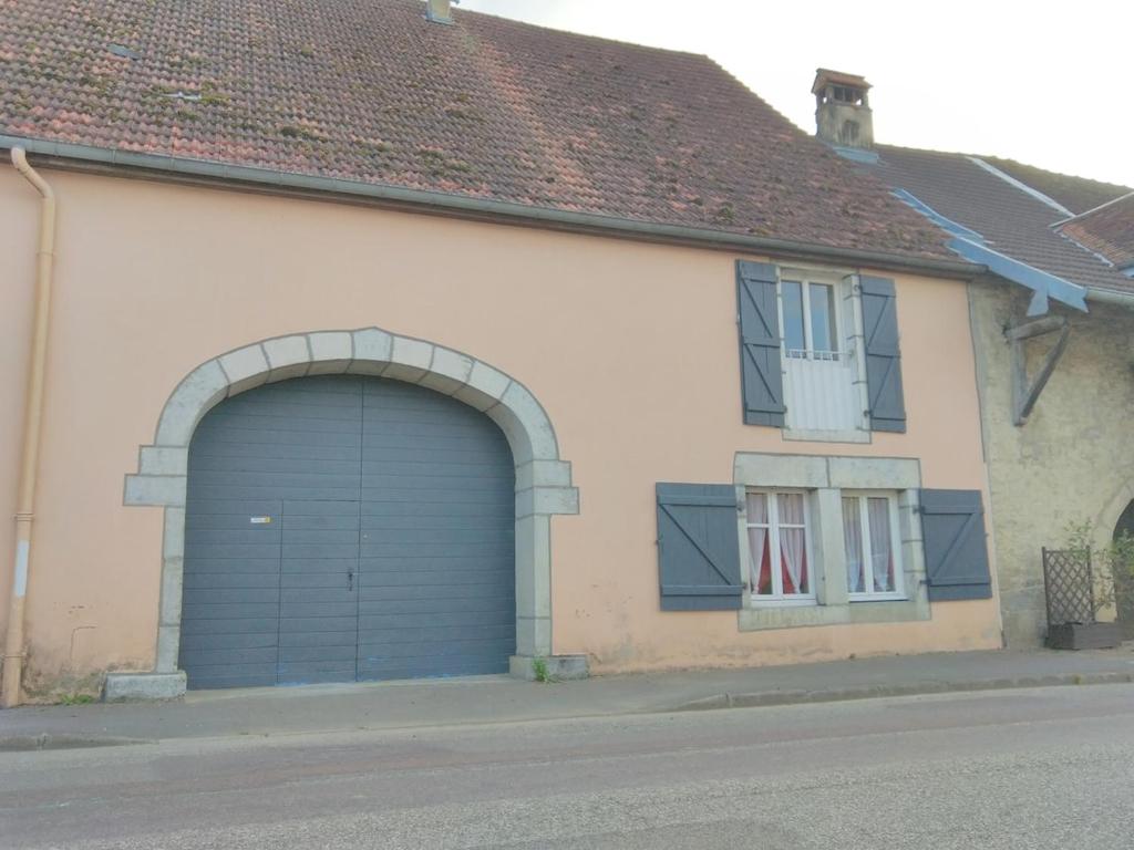 a garage with a blue door on the side of a house at F2 appartement de campagne in Cramans