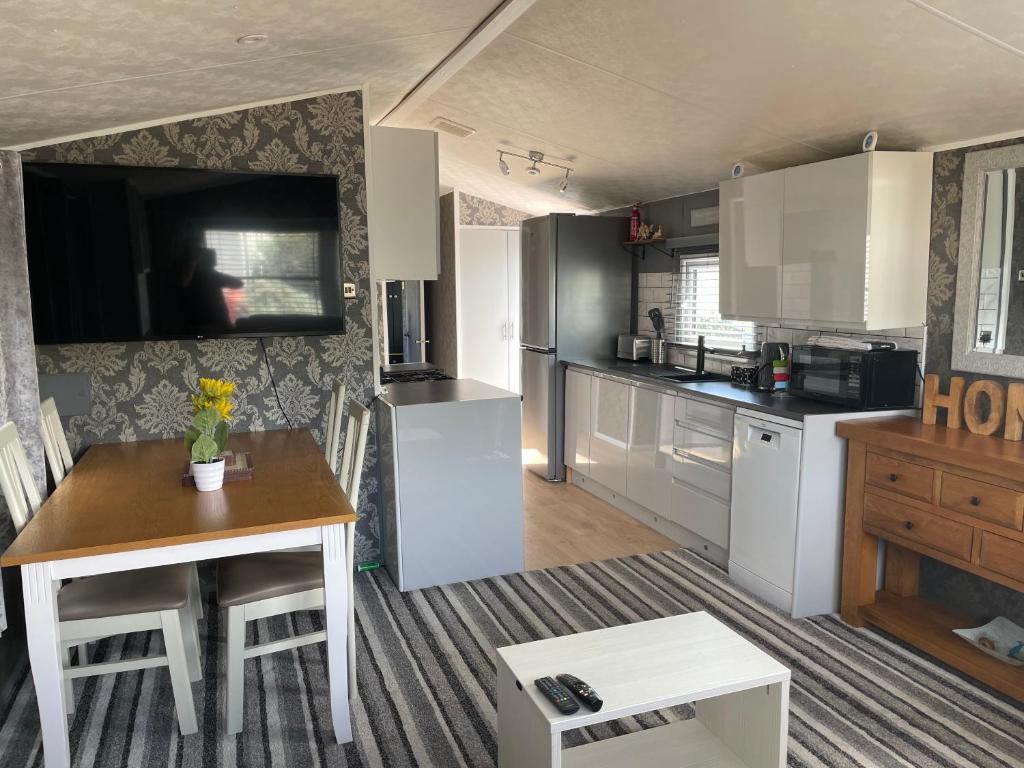 a kitchen with white cabinets and a wooden table at Tingdene caravan park in Gunton