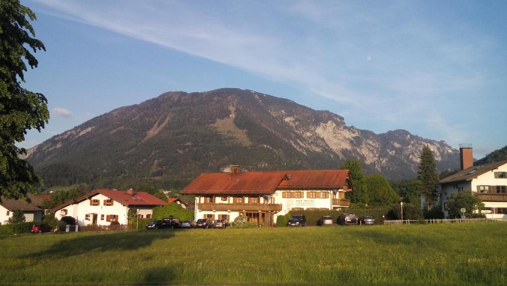 een huis in een veld met een berg op de achtergrond bij Kurhotel Rupertus in Bad Reichenhall