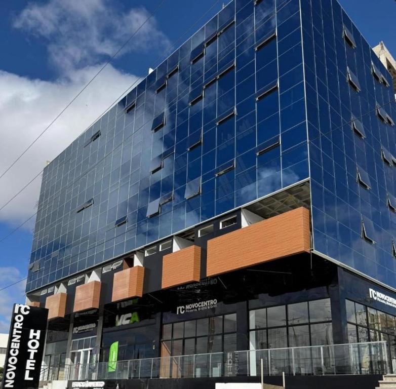 a tall glass building with a sign in front of it at Apartamento 107 Hotel Novo Centro in Petrolina