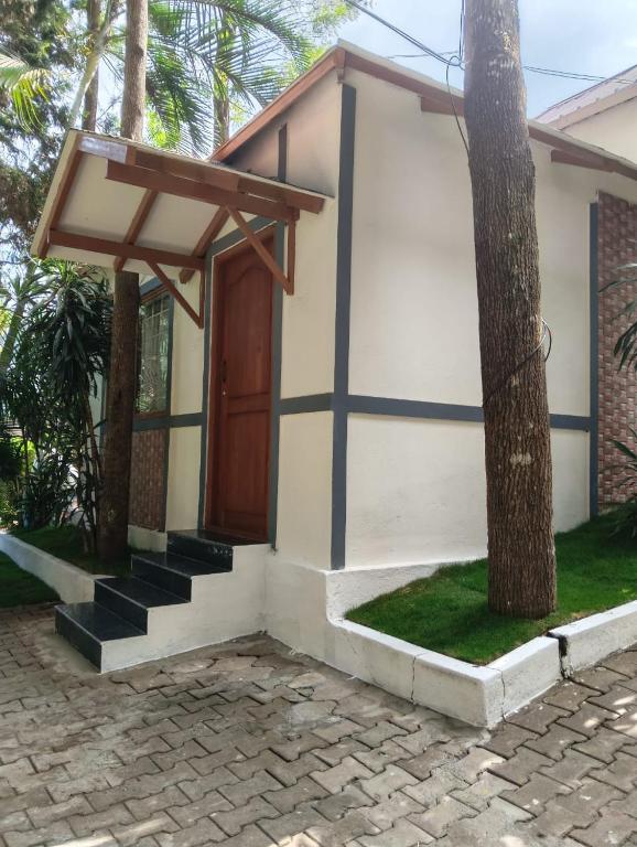 a small house with a wooden door and stairs at Alpine Cloud Resort in Yercaud