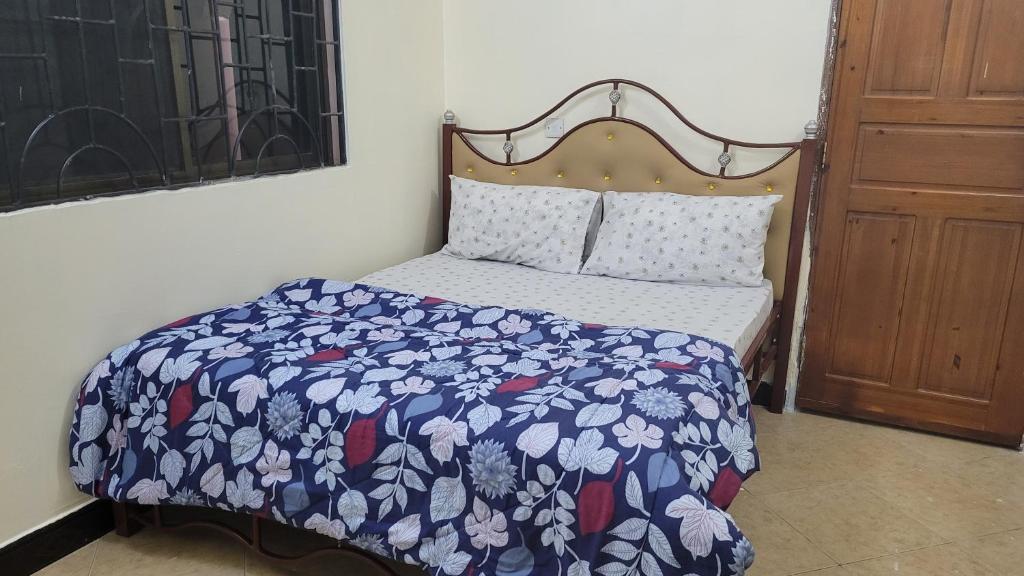 a bedroom with a bed with a blue and white comforter at Milele Homestay in Boma la Ngombe