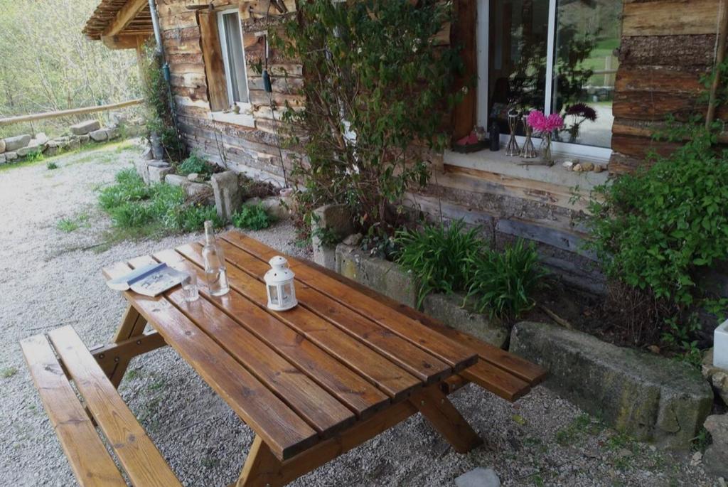 une table de pique-nique en bois devant une maison dans l'établissement Petit coin de paradis en Ardèche, à Saint-Julien-Boutières