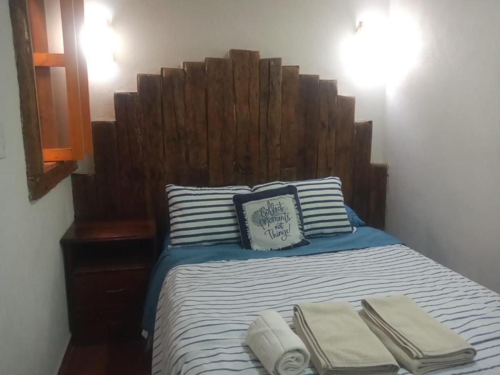 萨卡特兰Posada Las vigas的一张带木制床头板和毛巾的床