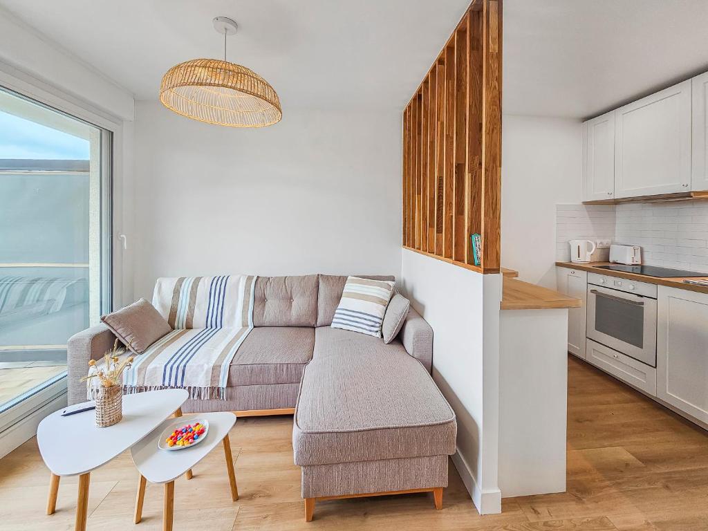 un salon avec un canapé et une table dans l'établissement South-facing terrace, direct beach access, à Cabourg