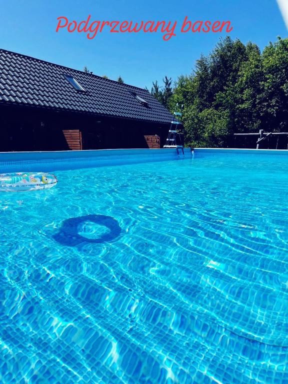basen z niebieską wodą przed budynkiem w obiekcie Domki Arkadia Mielno w mieście Mielno
