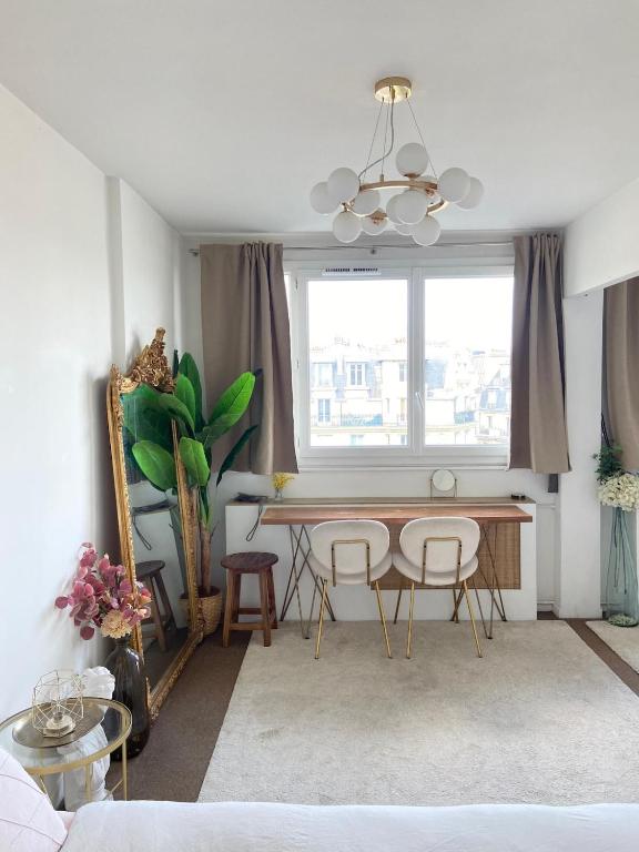 un soggiorno con tavolo, sedie e finestra di Eiffel Tower View - Charming Suite a Parigi