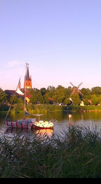 two boats in the water with a windmill in the background at Ferienwohnung Inselblüte in Werder