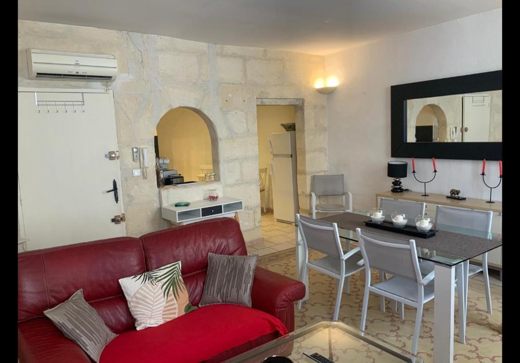 un salon avec un canapé rouge et une table dans l'établissement La maison des arènes, à Arles