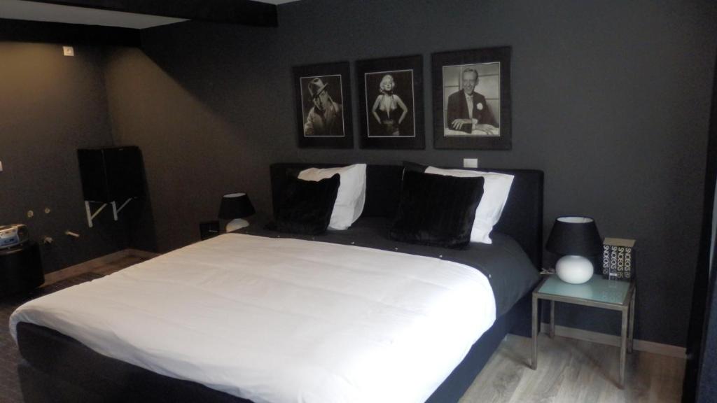 1 dormitorio con 1 cama blanca grande con almohadas negras en Studio frodo en zazou, en Maaseik