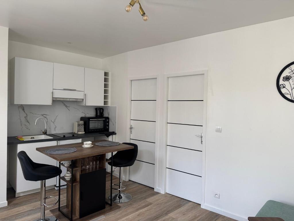eine Küche mit weißen Schränken und einem Tisch und Stühlen in der Unterkunft Appartement Meli in Villeneuve-sur-Bellot