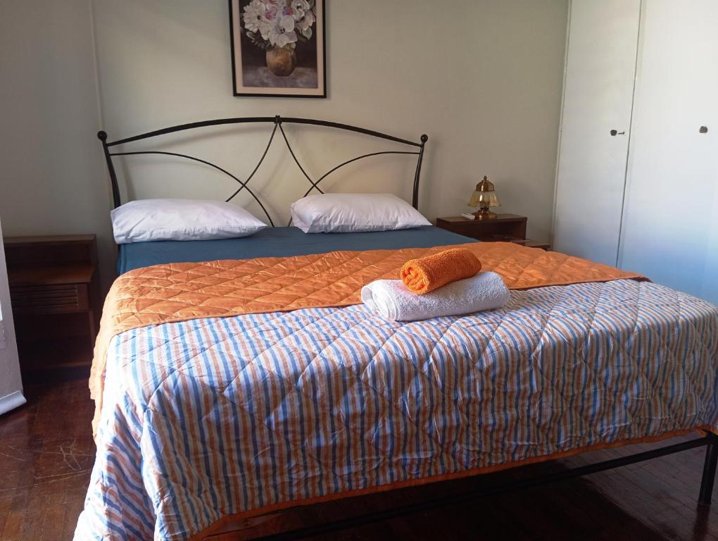 a bedroom with a bed with an orange towel on it at Comfort bed in a room 5' from metro in Athens