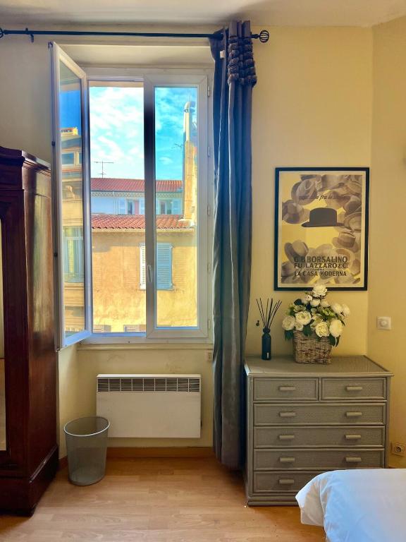 une chambre avec une fenêtre et une commode et une commode avec des fleurs dans l'établissement Panter Properies Studio, à Cannes