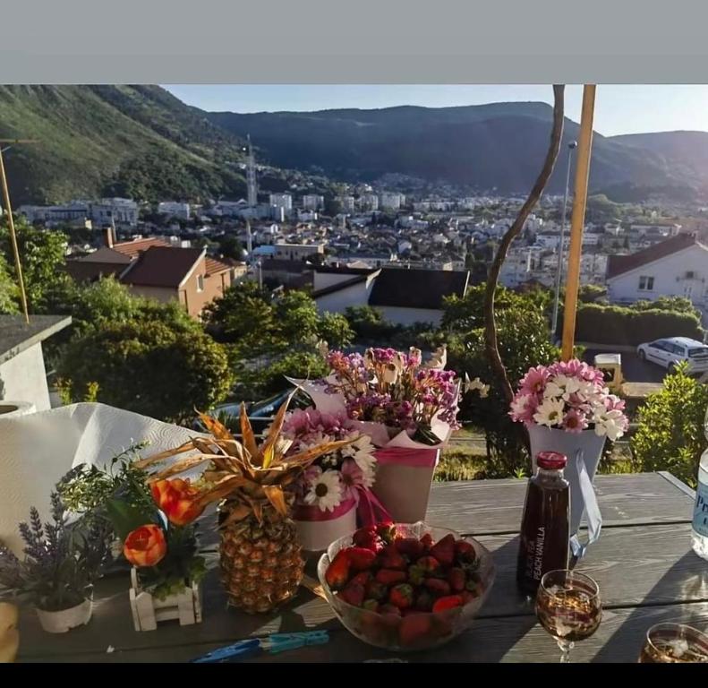Una mesa con flores y frutas con vistas. en Apartments Cinderella with City View, en Mostar