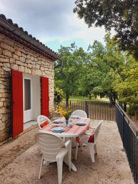 - une table et des chaises sur une terrasse avec une porte rouge dans l'établissement GITE des VERGIERS, à Murs