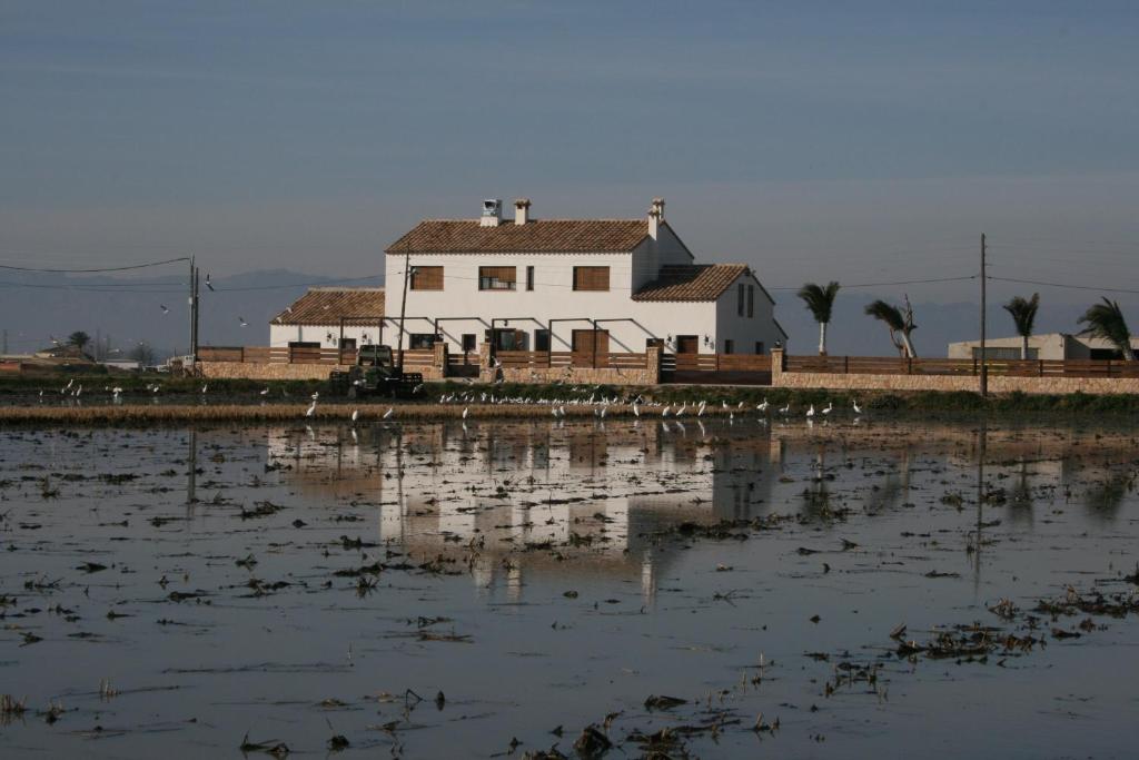 una casa blanca en la orilla de un cuerpo de agua en Masia Tinet, en Deltebre