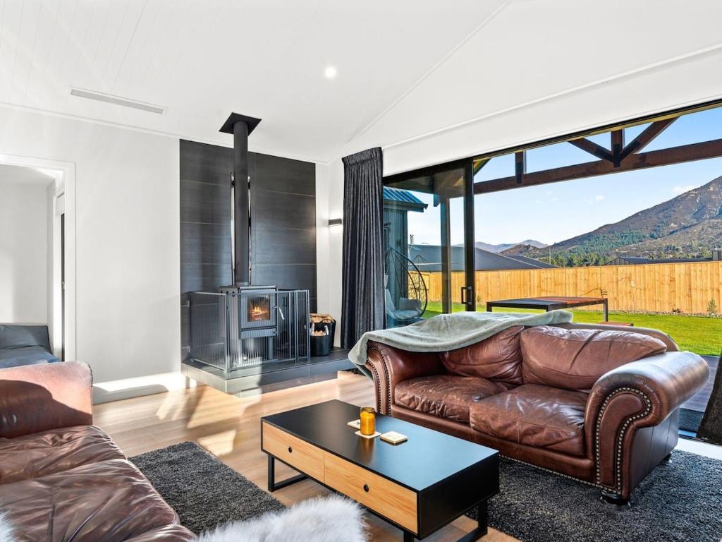a living room with a leather couch and a fireplace at Entire Hawea Holiday Home near Wanaka 2-10 guests in Lake Hawea
