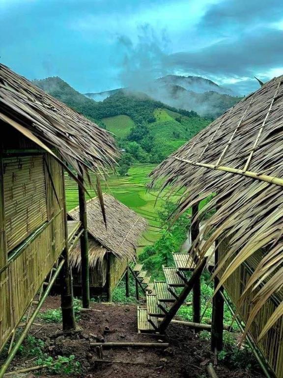 a group of huts with mountains in the background at บ้านไม่ไผ่บ้านเวร-BambooHouse Banwen in Ban Khun Nam Nan
