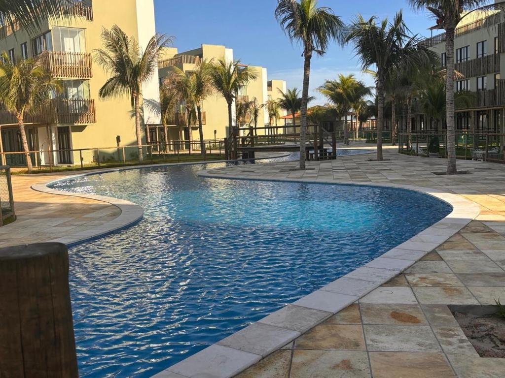 a swimming pool with palm trees and buildings at Encanto Moanara in Luis Correia