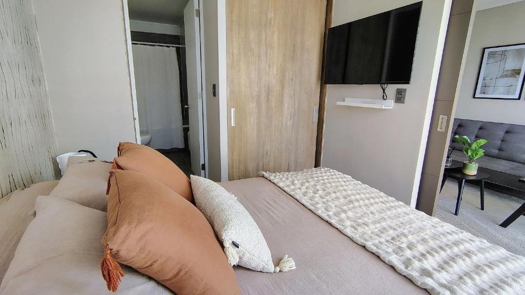 a bedroom with a couch with pillows and a television at Encantador departamento en Barrio Ñuñoa in Santiago