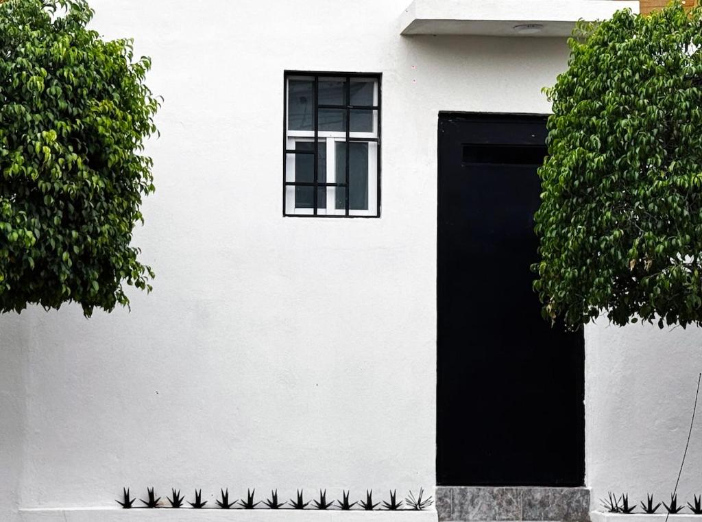 a white house with a black door and a window at Departamento en Querétaro in Querétaro