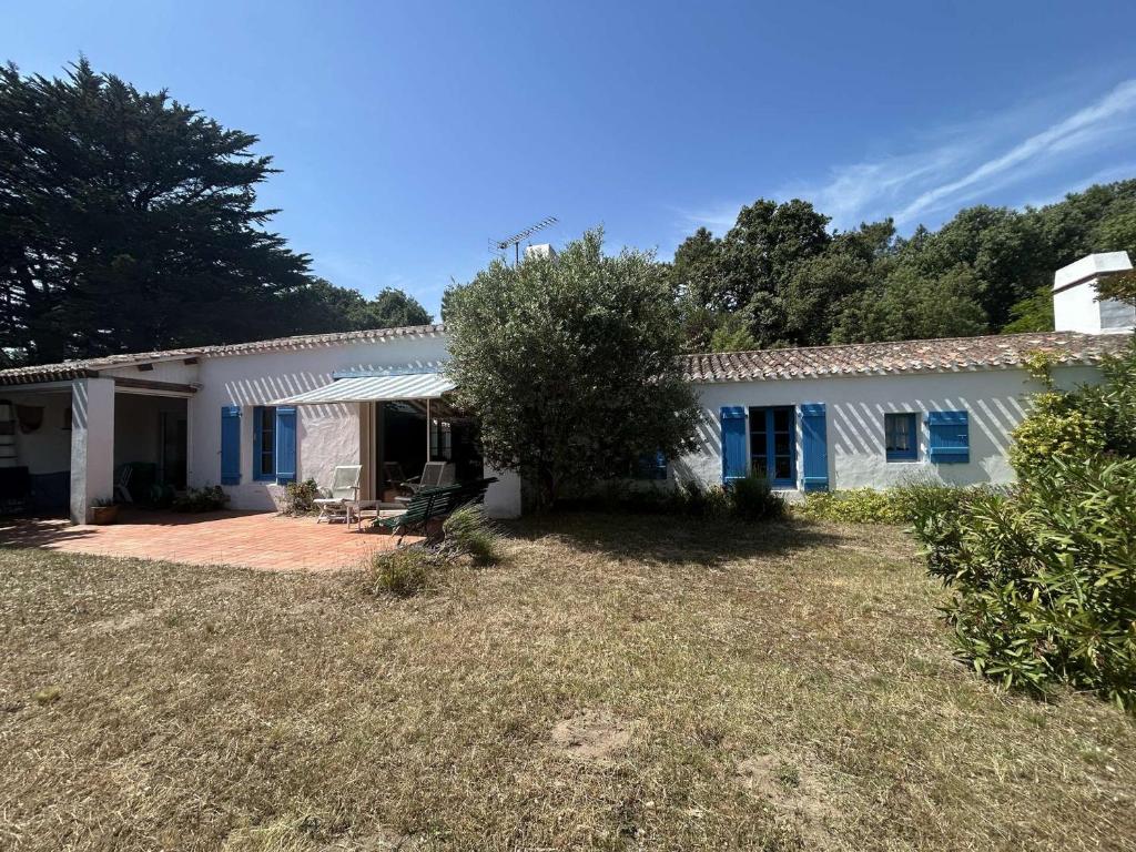 une maison blanche avec des fenêtres bleues et une cour dans l'établissement Maison Noirmoutier près plage, 5 pièces, 7 couchages - FR-1-224B-246, à Noirmoutier-en-l'lle