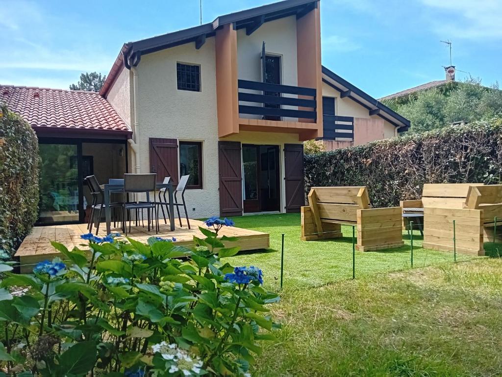 une maison avec une arrière-cour dotée d'une table et de chaises dans l'établissement Villa à Seignosse : près forêt et océan, terrasse, parking gratuit - FR-1-239-1129, à Seignosse