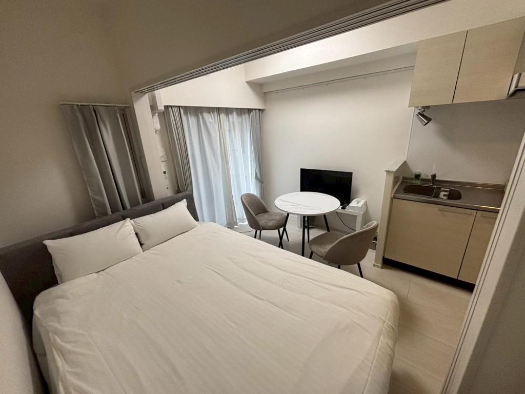 福岡市にあるStar Residence2 春吉中洲の白いベッドと小さなテーブルのある寝室