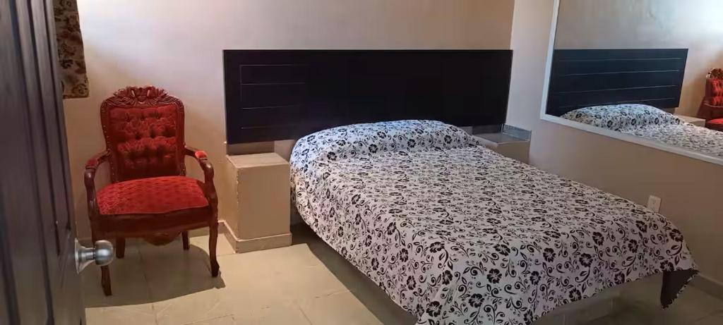 a bedroom with a bed and a red chair at Posada Casa Blanca in Cedro