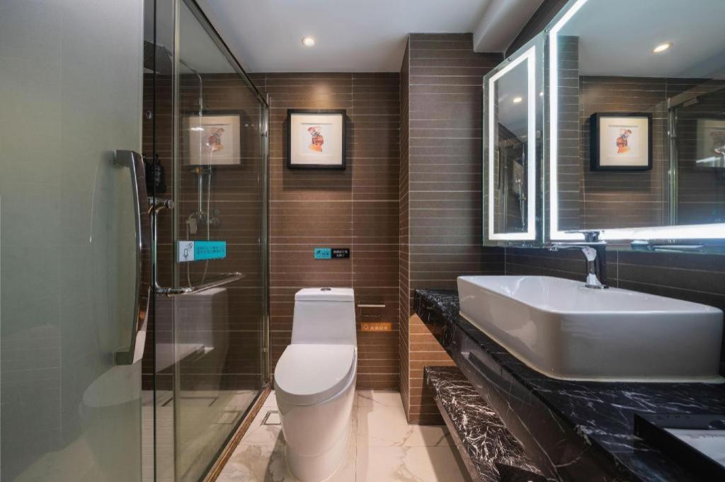 a bathroom with a sink and a toilet and a mirror at Xana Hotelle Xiamen Airport Zone Government in Xiamen