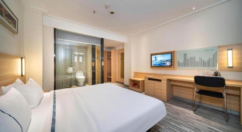 a hotel room with a large bed and a desk at City Comfort Inn Wuhan East Lake Scenic Area Happy Valley in Wuhan