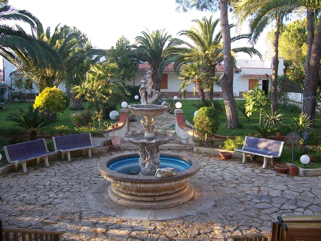 a fountain in a courtyard with benches and palm trees at Villa Chiara - Vittoria in Vittoria