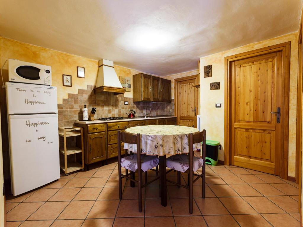 a kitchen with a table and a refrigerator at Appartamento Dal Maestro Serafino in Pragelato